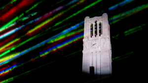 NC State Memorial Belltower at night with colored lasers in foreground.
